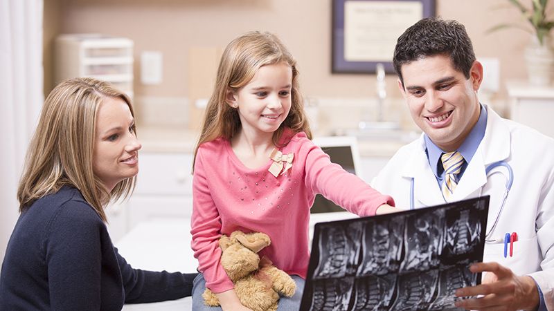 photo of doctor reviewing x-ray with child and parent