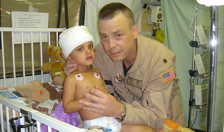 Stephen Barnes, MD, poses with a young patient in 2006 at a U.S. military hospital in Balad, Iraq.
