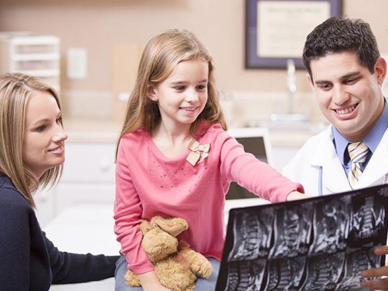 photo of doctor reviewing x-ray with child and parent