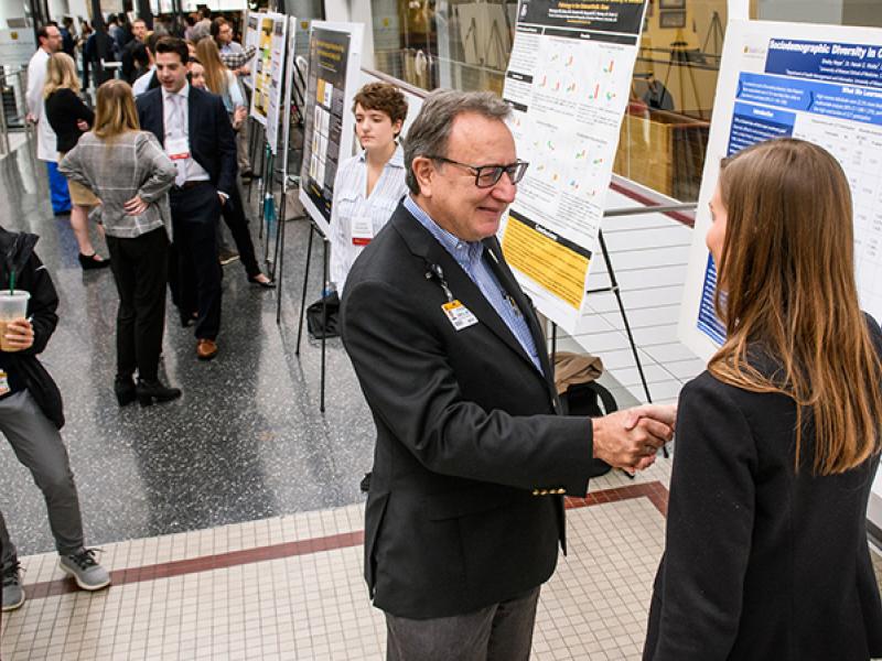 Dean Zweig reviewing a student's poster at Health Sciences Research Day