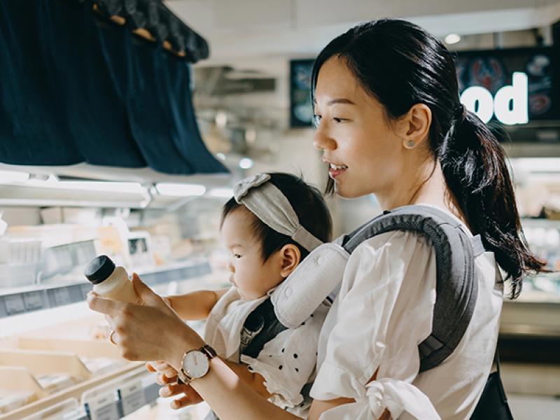 Asian woman grocery shopping with a baby
