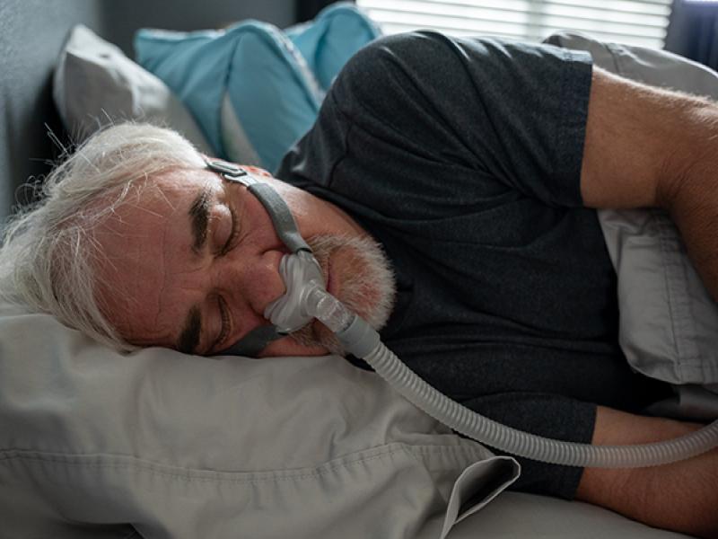 Mature Man With Sleep Apnea Wearing A CPAP Mask In Bed Sleeping